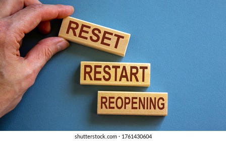 Wooden Blocks Form The Words 'reset, Restart, Reopening' On Blue Background. Male Hand.