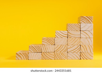 Wooden blocks forming stairway on yellow background. Ladder of success, business investment growth, success or career path success concept. Personal development