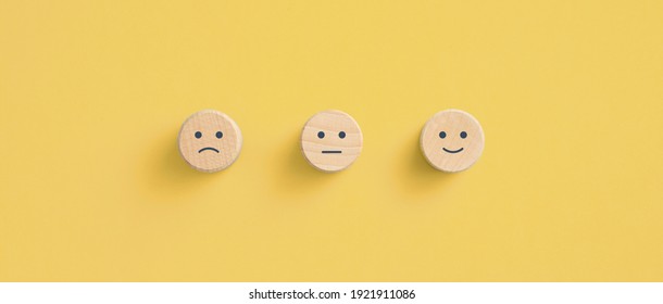 Holzblöcke mit dem Happy-Gesicht-Lächelsymbol auf gelbem Hintergrund, Bewertung, Erhöhung der Bewertung, Kundenerfahrung, Zufriedenheit und bestes Dienstleistungsbewertungs-Konzept