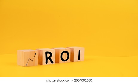 Wooden blocks with icon of growth and text "ROI". Isolated with yellow background. - Shutterstock ID 2054091680