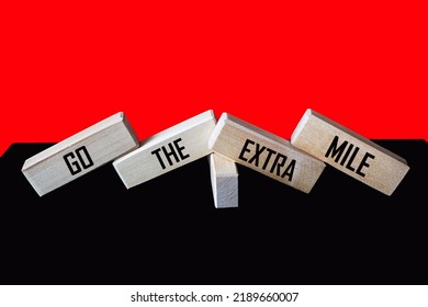 Wooden Blocks With The Inscription Go The Extra Mile On A Black And Red Background. Business And Go The Extra Mile Concept. Copy Space.