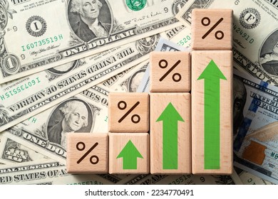 Wooden blocks with interest rate percent of bank with US dollars, financial world economy crisis design concept over blue table background. - Shutterstock ID 2234770491