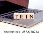 Wooden blocks with the letters TRIN placed on a laptop keyboard on a wooden desk 