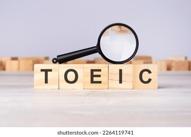 wooden blocks with a magnifier text: TOEIC - Test Of English For International Communication