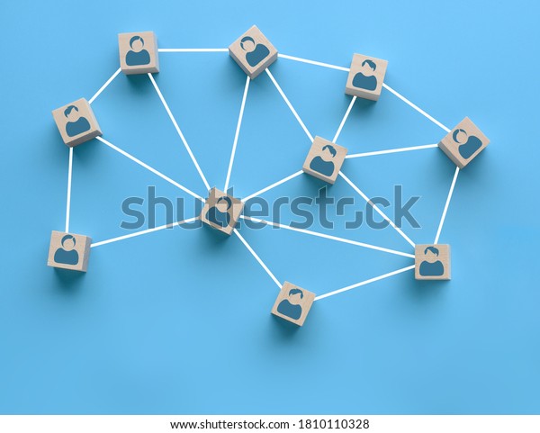 Wooden blocks\
with people icon interconnected by white lines on blue background.\
Cooperation, teamwork, business training concept. Social\
connections, joining to solve\
tasks