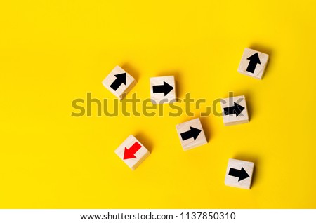 Wooden blocks with red arrow facing the opposite direction black arrows, Unique, dissenting opinion, individual and standing out from the crowd. divergent views