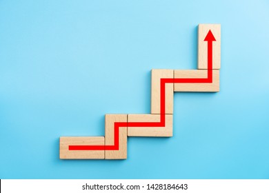Wooden blocks stacking as step stair with red arrow up, blue background, Business growth success process concept, copy space