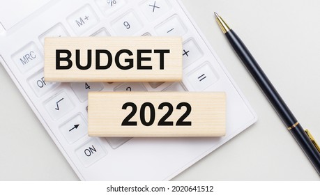 Wooden blocks with the text BUDGET 2022 lie on a light background on a white calculator. Nearby is a black handle. Business concept - Shutterstock ID 2020641512
