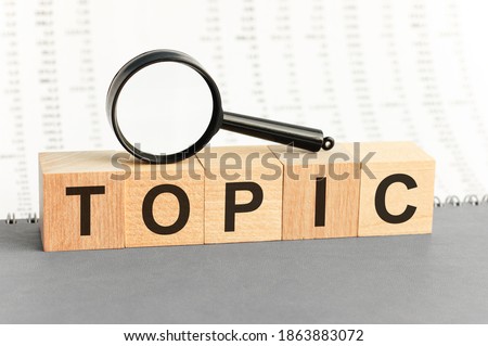 Wooden Blocks with the text: topic with magnifying glass. Topic word made with building blocks. Business concept