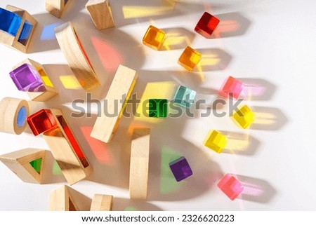 Wooden blocks with translucent rainbow stones on white background. Colorful toys for Kids.  Educational game for toddler. Play with light and exploring coloured shadows. 