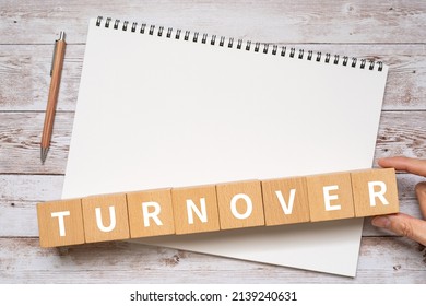 Wooden blocks with "TURNOVER" text of concept, a pen, a notebook, and a hand. - Shutterstock ID 2139240631