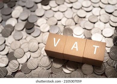Wooden blocks with "VAT" text of concept and coins.