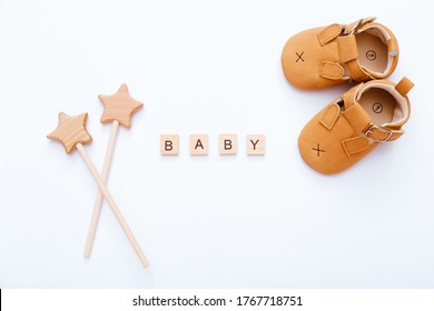 Wooden Blocks With Word Baby, Booties And Wooden Stars Near It On White Background. Top View