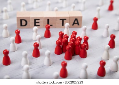 wooden blocks with the word delta surrounded by white and red wooden figurines. symbol for corona mutant delta.
