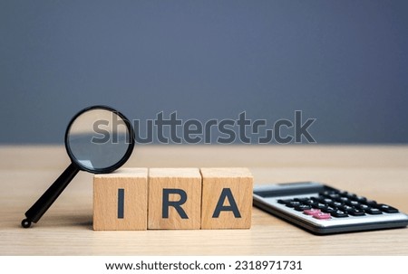 Wooden blocks with the word IRA - individual retirement account. Tax-advantaged account that individuals use to save and invest for retirement. Business and finance concept