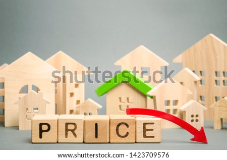 Wooden blocks with the word Price, down arrow and miniature houses. Reduced housing prices. The fall and crisis of the real estate market. Bankruptcy. Cheap property loans. Lower rent value