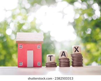 Wooden blocks with the word TAX on stack of coins and miniature house. The concept of payment tax for house, Property investment, House mortgage, Real estste. - Shutterstock ID 2382503313