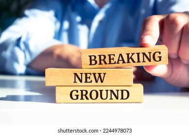 Wooden blocks with words 'BREAKING NEW GROUND'. Business concept
