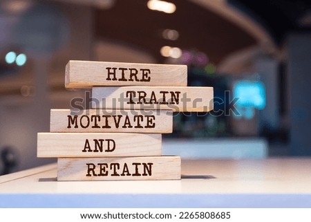 Wooden blocks with words 'Hire, Train, Motivate and Retain'.