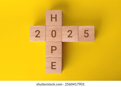 Wooden blocks with the words 'HOPE 2025' on a yellow background, symbolize clear goals and aspirations for the coming year. Focus and planning for future achievements. - Powered by Shutterstock