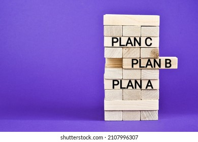 Wooden blocks with words PLAN A, PlAN B, PLAN C on violet background with copy space. Wooden tower. Business strategy, failure analysis and not give up. Business concept