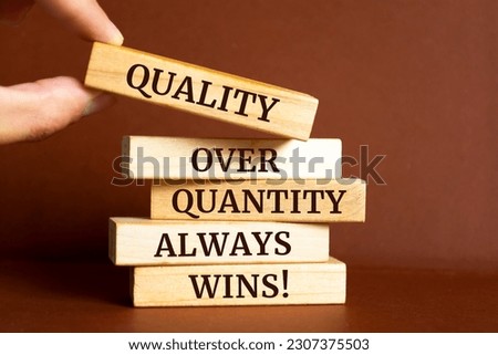 Wooden blocks with words 'quality over quantity always wins'.