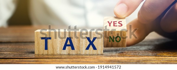 Wooden blocks with the words Tax, yes or no. Taxes\
payment concept. Tax evasion. Taxation. Business and finance.\
Choose, make a choice