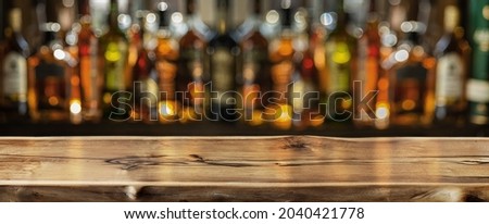 Wooden board and beautiful bokeh shelves with alcohol bottles at the background. Bar concept. Clipping path.