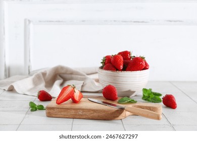 Wooden board and bowl with sweet fresh strawberries on white tile table - Powered by Shutterstock