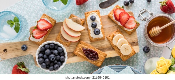 A wooden board of breakfast crackers topped with spreads and fresh toppings. - Powered by Shutterstock