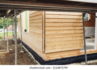 Wooden board cladding on a prefabricated new build house under construction in a corner angle view of the exterior of the building