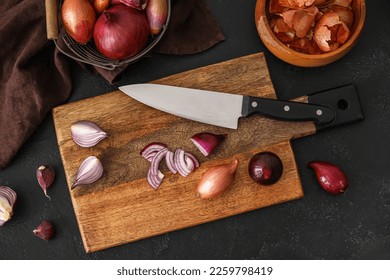 Tablero de madera con cebolla roja cortada y cuchillo sobre fondo oscuro