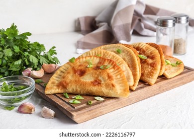 Wooden board with delicious chebureks on light background - Shutterstock ID 2226116797