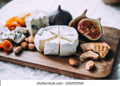 Wooden board with different kinds of cheese and dried fruits. Dinner or aperitivo party concept.
