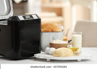 Wooden board with dough and bread machine on table - Shutterstock ID 657354181