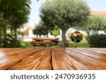 Wooden board of empty space and blurred background of grill in garden. Warm summer time day. 