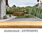 Wooden board of empty space and blurred background of grill in garden. Warm summer time day. 