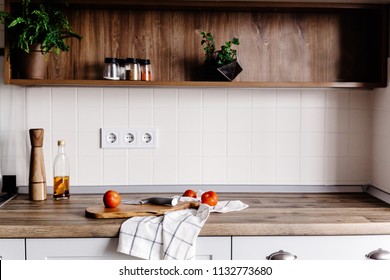 wooden board with knife, olive oil, tomatoes, towel on modern kitchen countertop and shelf with spices and plants. cooking food. Stylish kitchen interior design in scandinavian style - Powered by Shutterstock