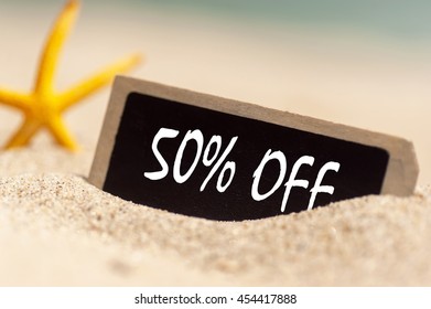 wooden board on sunny sandy beach  with text 50% off