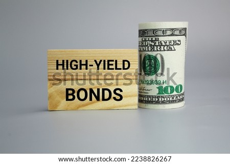 wooden board and paper money with the words High-Yield Bonds. Business and finance concept