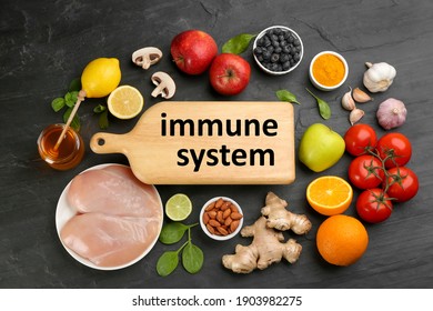 Wooden board with phrase Immune System and fresh products on dark grey background, flat lay - Shutterstock ID 1903982275