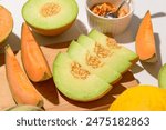 Wooden board with ripe cut melons on white background