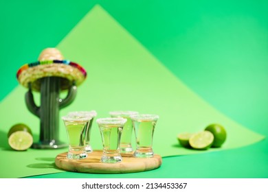 Wooden board with shots of tasty tequila on color background
