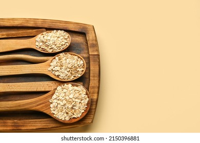 Wooden board with spoons of raw oatmeal on color background - Shutterstock ID 2150396881