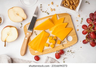 Wooden board with tasty cheddar cheese on light background - Powered by Shutterstock