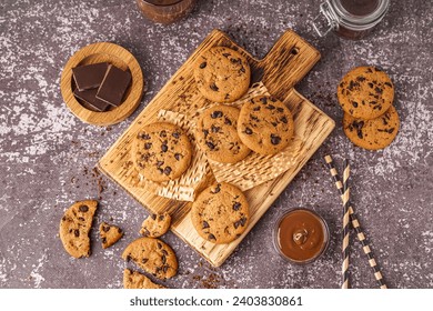 Wooden board of tasty cookies with chocolate chips and sauce on grey background - Powered by Shutterstock