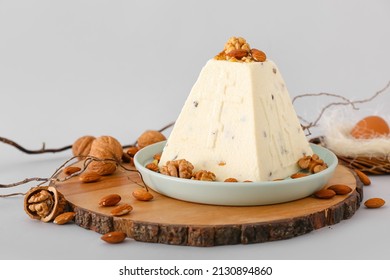 Wooden board with tasty curd Easter cake and nuts on light background