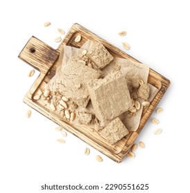 Wooden board with tasty halva and peanuts on white background