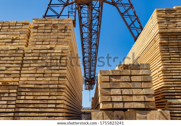 Wooden boards, lumber, industrial\
wood, timber.  Finished products under an industrial\
crane.