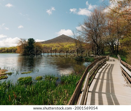 A wooden boardwalk over Abbott Lake and view of Sharp Top Mountain at, Peaks of Otter on the Blue Ridge Parkway, Virginia